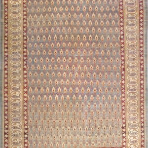 Blue-gray rug with repeating light motifs in the center field and large cream paisley borders.