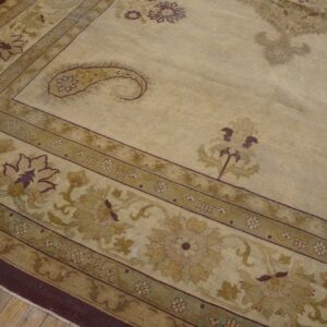 Traditional patterned rug in beige, olive, and maroon lying on rustic wood plank flooring.