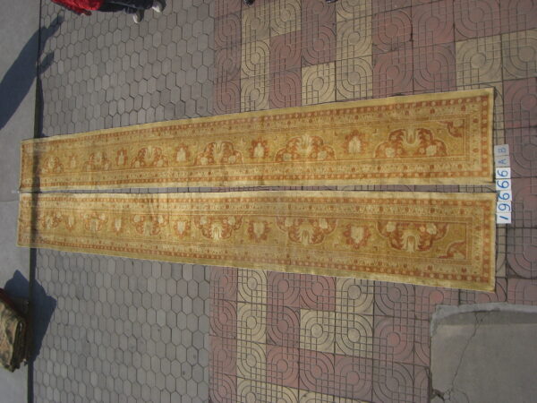 Two long, gold and terracotta runner rugs with classical patterns are placed on patterned outdoor paving.