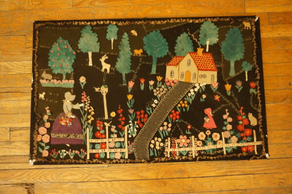 Colorful folk art rug depicting a house, figures, and garden on a dark ground, laid on wood flooring.