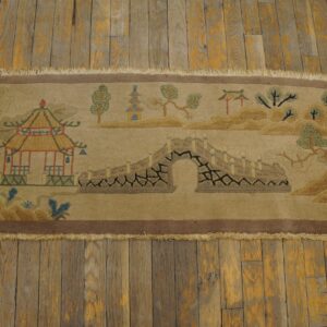 Tan scenic runner rug featuring a pagoda, arched bridge, and trees, lying on distressed wood planks.