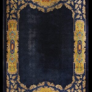 Dark blue rug with a subtle field pattern and an elaborate gold, yellow, and multicolored floral border.