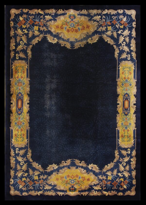 Dark blue rug with a subtle field pattern and an elaborate gold, yellow, and multicolored floral border.