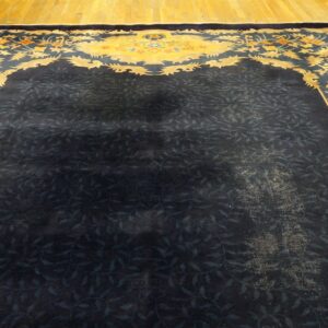 Dark blue rug with a subtle vine pattern and a contrasting yellow border featuring stylized flowers.