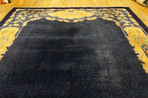 Dark blue rug with a subtle vine pattern and a contrasting yellow border featuring stylized flowers.