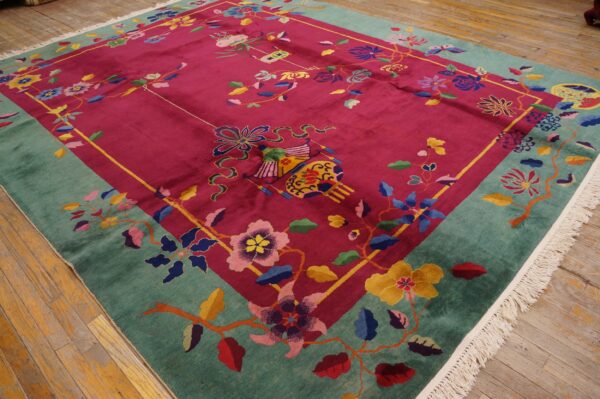 Multi-colored floral rug featuring a magenta field and teal border laid on aged wood floors.