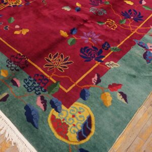 Colorful floral rug with magenta field and teal border featuring fringe on rustic wood flooring.