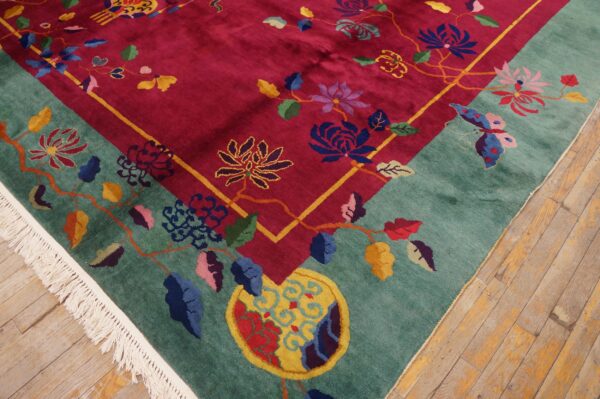 Colorful floral rug with magenta field and teal border featuring fringe on rustic wood flooring.
