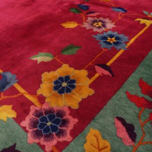 High-pile rug corner showing a bright pink field and teal border with bold multicolor flowering vines.