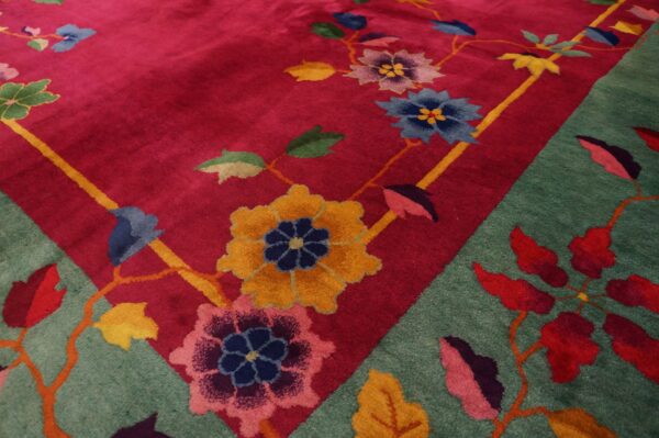 High-pile rug corner showing a bright pink field and teal border with bold multicolor flowering vines.