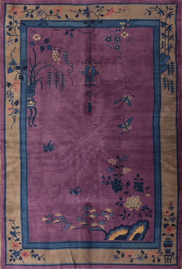 Magenta rug with a blue and tan border and traditional chinese botanical and insect designs.