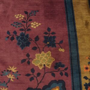 Deep mauve rug with stylized navy and mustard floral vines next to a wide tan and teal striped border.