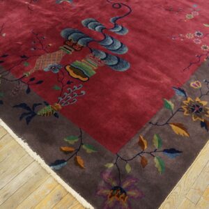 Ornate deep red and brown rug with shimmering high pile and multi-colored flower and vase motifs on wood flooring.