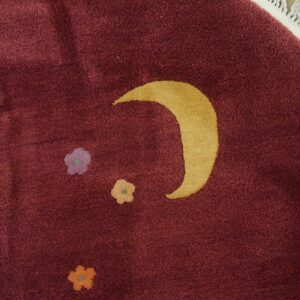 Plush burgundy rug featuring a golden crescent moon and scattered small flowers on light wood flooring.