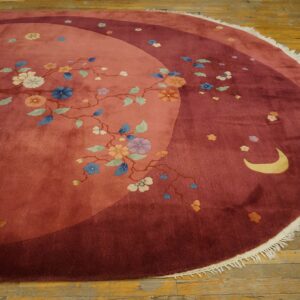 Round rug featuring rose and maroon fields, flowering vines, and a crescent moon on wood floors.