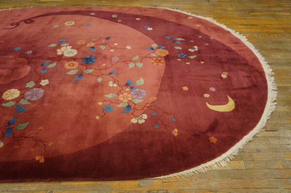 Round rug featuring rose and maroon fields, flowering vines, and a crescent moon on wood floors.