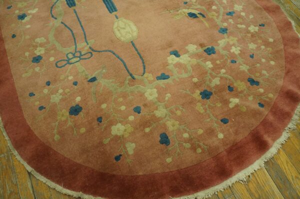 Round salmon-colored rug featuring a teal and pale green floral vine pattern with a rust border on wood floors.