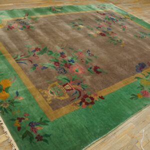 Green and brown rug with large scattered multicolor floral designs sits on natural wood planks.