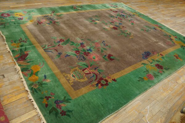Green and brown rug with large scattered multicolor floral designs sits on natural wood planks.