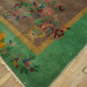 Brown and green rug with multicolored floral and foliage pattern displayed on light hardwood floor.