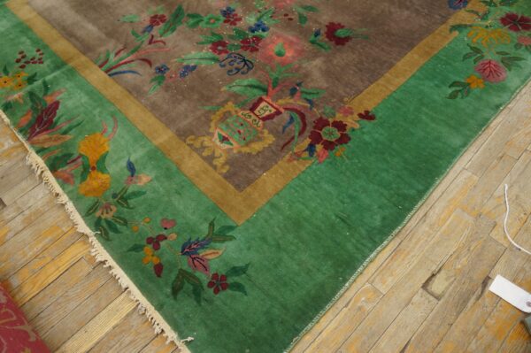 Brown and green rug with multicolored floral and foliage pattern displayed on light hardwood floor.