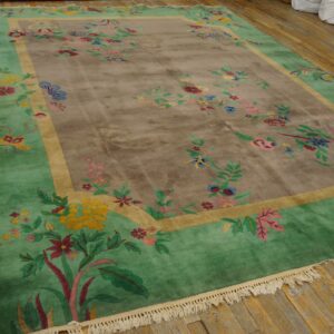 Multicolored floral rug featuring a taupe center and a bright green border lying on worn wooden planks.