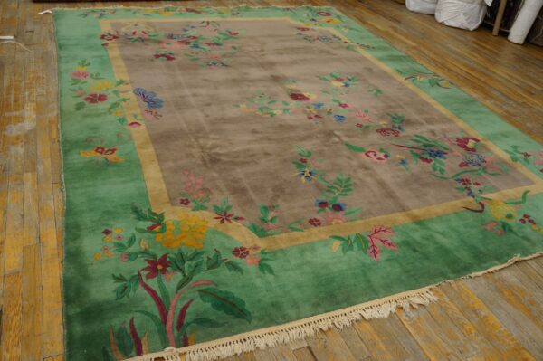 Multicolored floral rug featuring a taupe center and a bright green border lying on worn wooden planks.