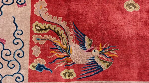 A red high-pile rug detail shows a colorful stylized bird motif and a light tan border with blue scrolls.
