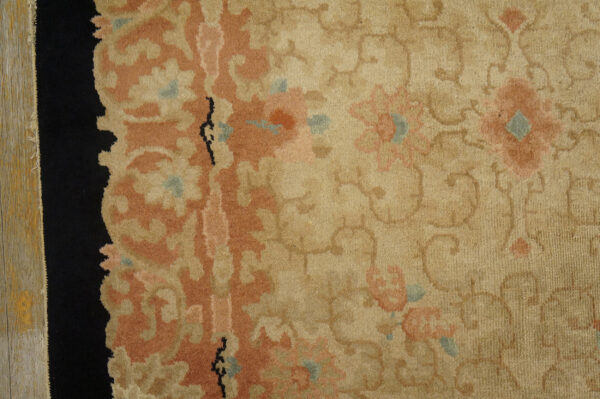 Matching floral rugs in pink and beige with black borders are laid on a distressed wood floor.