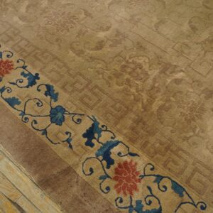 Tan rug with subtle tone-on-tone patterns and a blue and red floral border on distressed wood planks.