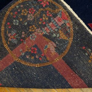 A navy blue rug is folded back, revealing the patterned reverse side and a red flower on the plush pile.