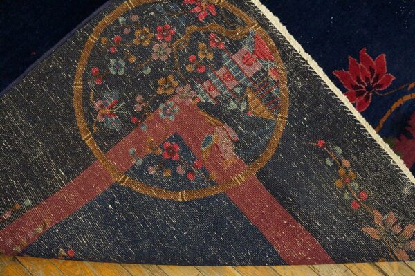 A navy blue rug is folded back, revealing the patterned reverse side and a red flower on the plush pile.