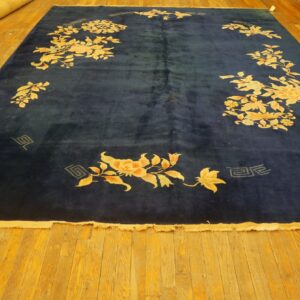 Plush navy blue rug featuring large gold and peach floral designs on bright amber wood flooring.