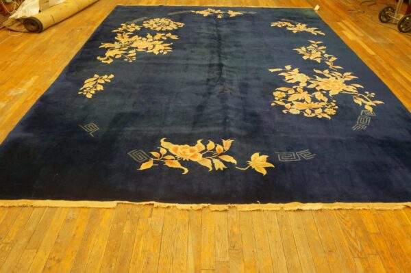 Plush navy blue rug featuring large gold and peach floral designs on bright amber wood flooring.