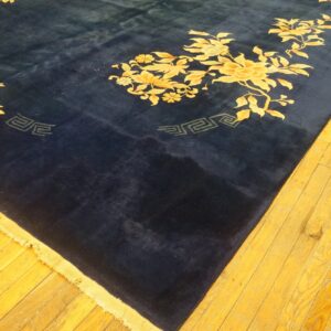 Plush navy rug with yellow floral vines and geometric accents lies on bright golden wood floorboards.
