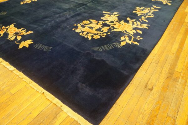 Plush navy rug with yellow floral vines and geometric accents lies on bright golden wood floorboards.