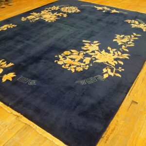 Large navy blue rug with gold and apricot floral motifs on a warm tone wood plank floor.