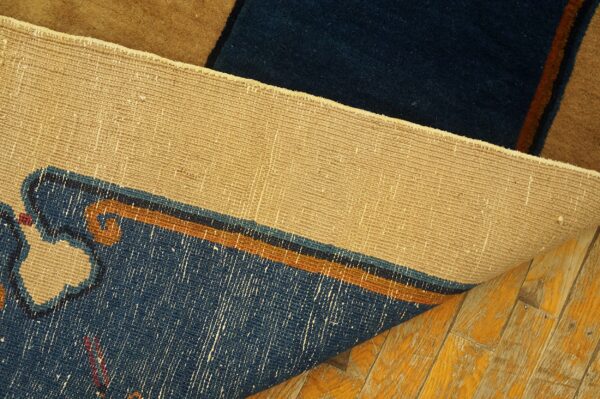 The tan woven backing of a blue and brown patterned rug is visible above glossy, worn hardwood floors.