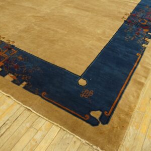 Tan rug featuring a wide, patterned dark blue border with orange and red details on wood floorboards.