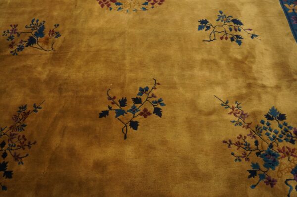 Golden ochre rug with scattered blue and red floral sprays, showing a visible blue border edge.