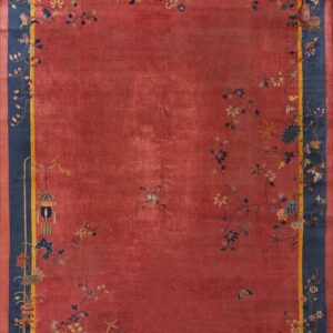 Reddish-pink rug with a wide navy border and yellow stripe accented by cascading floral and vase motifs.