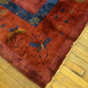 Plush red rug featuring blue and yellow floral and butterfly motifs on distressed wood flooring.