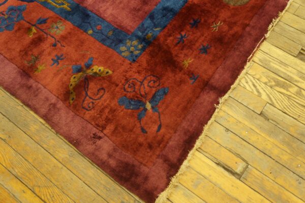 Plush red rug featuring blue and yellow floral and butterfly motifs on distressed wood flooring.