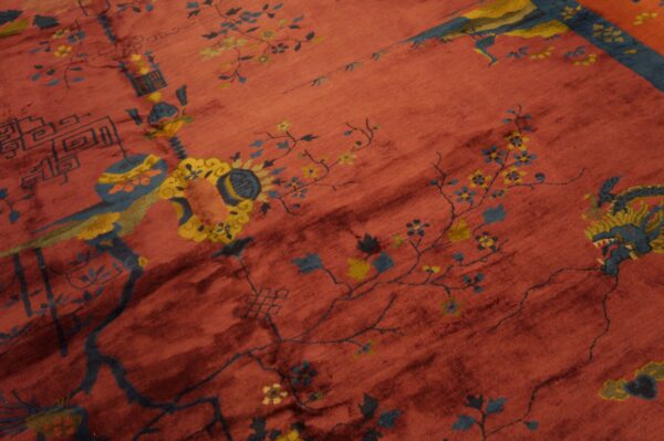 Reddish rug detail showing blue and yellow mythical creatures, flowering vines, and geometric elements.