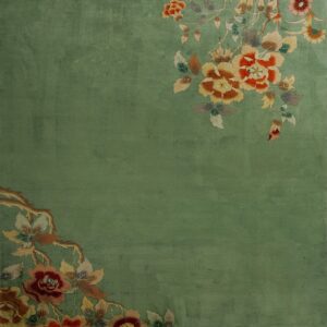 Plush sage green rug featuring orange, red, and yellow floral designs diagonally across two corners.