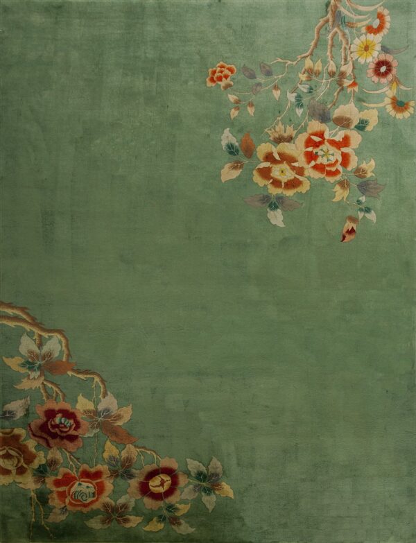 Plush sage green rug featuring orange, red, and yellow floral designs diagonally across two corners.