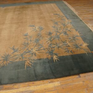 Tan and teal rug with carved bamboo leaf patterns rests on distressed wood flooring.