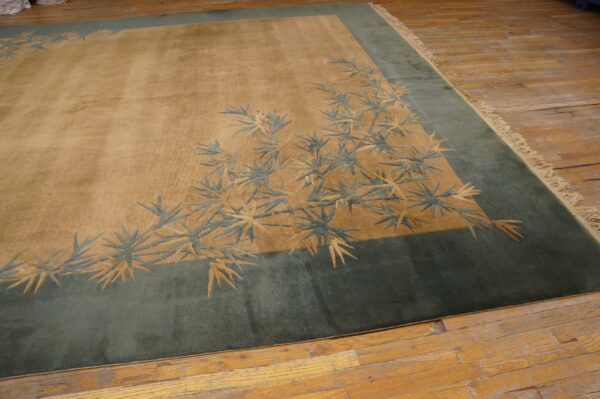 Tan and teal rug with carved bamboo leaf patterns rests on distressed wood flooring.
