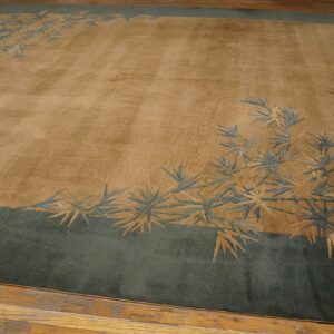 A plush golden-tan rug features a blue-green border and carved bamboo leaf design on wood flooring.