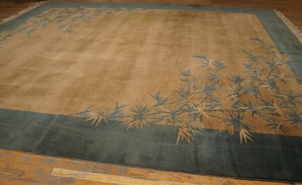 A plush golden-tan rug features a blue-green border and carved bamboo leaf design on wood flooring.